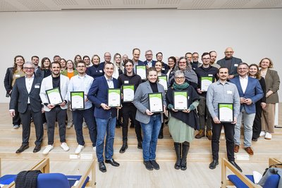 Rund 50 Personen stehen auf einem Bild mit Urkunden in den Händen